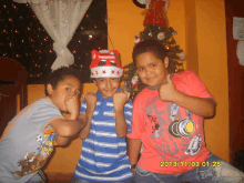 three young boys pose for a picture with a christmas tree in the background