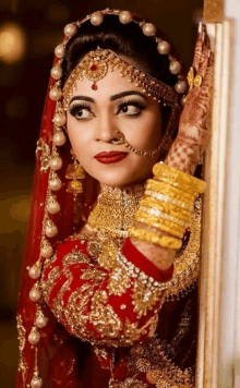 the bride is wearing a red and gold dress and jewelry .