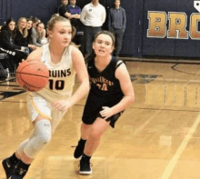 two girls are playing basketball on a court .