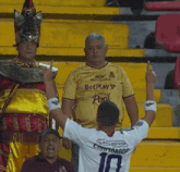 a man wearing a betplay shirt stands in a crowd