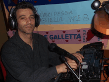 a man wearing headphones stands in front of a sign that says galletta