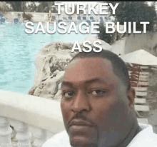 a man is standing in front of a pool with a turkey sausage built ass meme .