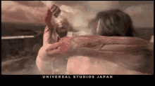 a poster for universal studios japan shows a man in a bathtub with a giant arm