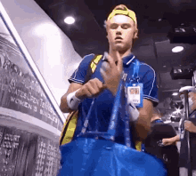 a man holding a blue bag in front of a wall that says ' united states open tennis ' on it