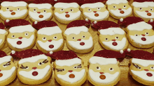 a row of santa cookies with white frosting and red hats