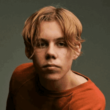 a young man with blonde hair is wearing a red sweater .