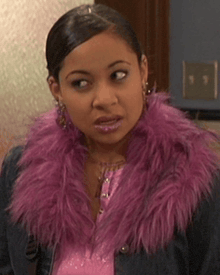 a woman wearing a pink fur collar and a denim jacket is looking at the camera .