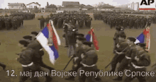 a large group of soldiers are marching in a field with flags in front of a sign that says ap