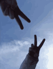 two people are making a peace sign with their hands in the air .