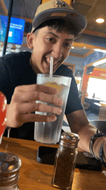 a man wearing a ny yankees hat is drinking from a glass with a straw