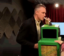 a man smoking a cigarette next to a green box that says ' a ' on it