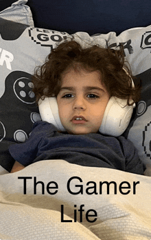 a young boy wearing headphones laying on a bed with the words the gamer life written on the bottom