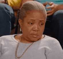 a woman is sitting in a chair with a necklace around her neck and making a funny face .