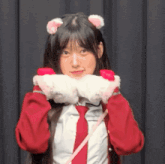 a girl wearing a cat ear headband and gloves looks at the camera