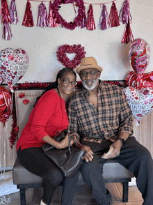 a man and woman are posing for a picture with valentine 's day balloons behind them