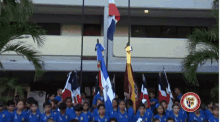 a group of children are holding flags in front of a building with a logo that says ' universidad ' on it