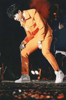 a man in an orange suit holds a microphone in his right hand