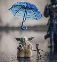 a baby yoda holding an umbrella next to a groot figure