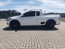 a white truck with black wheels is parked on a brick driveway