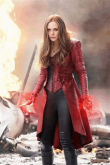 scarlet witch is wearing a red coat and black pants and holding a knife .