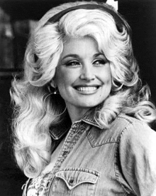 dolly parton is smiling in a black and white photo while wearing a denim shirt and hoop earrings .