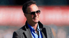 a man wearing sunglasses and a suit is standing in a stadium .