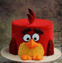 a red angry birds cake with a yellow bird on top of it .