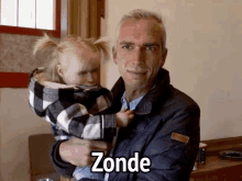 a man is holding a little girl with the word zonde written on the bottom