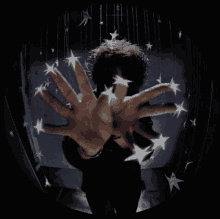 a man 's hands are reaching out towards a ceiling with stars hanging from it .