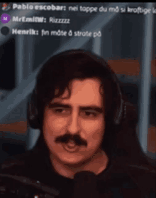 a man with a mustache is wearing headphones and looking at the camera .