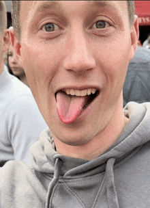 a man sticking his tongue out while wearing a grey sweatshirt