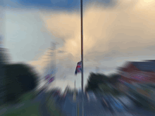 a blurry picture of a flag on a pole in front of a cloudy sky