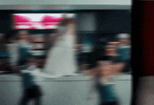 a blurry picture of people walking in front of a sign that says ' coca cola '