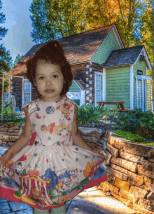 a little girl in a dress stands in front of a house