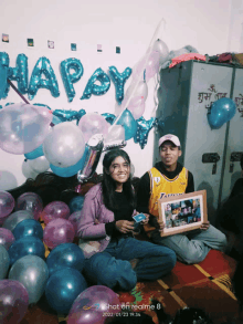 a man in a lakers jersey sits next to a woman in front of balloons that say happy