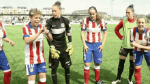 a group of female soccer players are standing on a field and one of them has the number 11 on her shorts