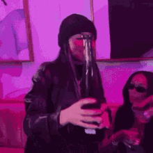 a woman is drinking from a bottle in a room with purple lights .