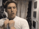 a man in a white shirt is adjusting his tie .