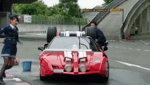 a woman in a police uniform is running towards a red car that has a license plate that says ' a ' on it