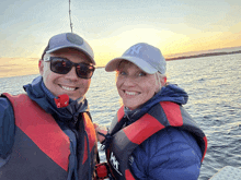 a man and a woman are standing in the water and the woman is wearing a new york yankees hat