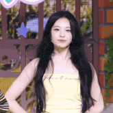 a woman with long black hair is wearing a yellow tank top that says another on it