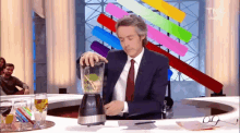 a man in a suit and tie is pouring liquid into a blender