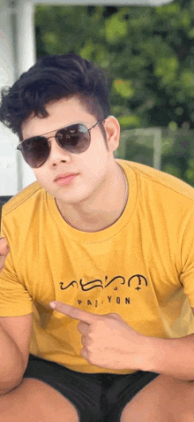 a young man wearing sunglasses and a yellow shirt with the word paiyon on it