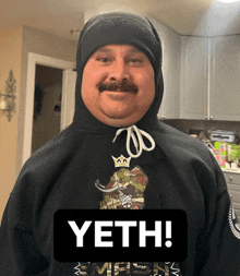 a man with a mustache is wearing a black hoodie that says yeth