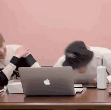 a man is sitting at a desk with a laptop and a hat on .