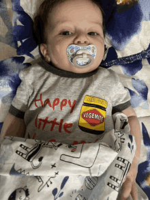 a baby with a pacifier is wearing a shirt that says happy little vegemite