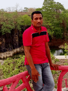 a man in a red shirt is leaning against a red railing