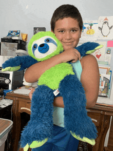 a boy is holding a stuffed sloth with a tag that says ' build a bear '