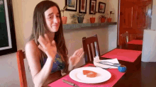 a woman is sitting at a table with a plate of food and a slice of tomato on it .