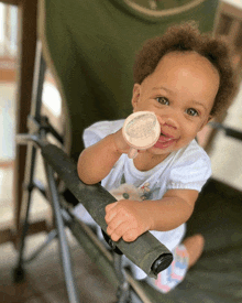 a baby is sitting in a chair with a bottle in her hand